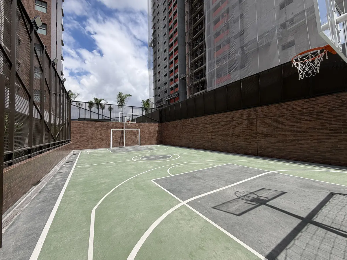Quadra recreativa do Florà Alphaville com piso verde e cinza demarcado, gol de futsal, tabela de basquete, muro de tijolinho e fechamento em tela metálica