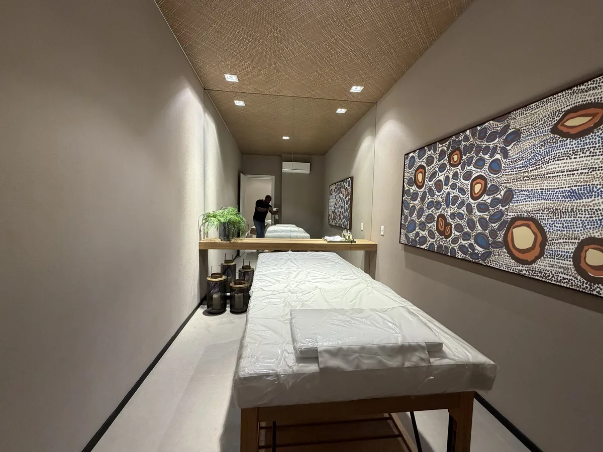 Sala de massagem do Florà Alphaville com maca de madeira, espelho na parede, lanternas decorativas e quadro colorido